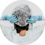 A woman wearing gloves attaching her disposable bouffant cap