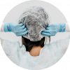 A woman wearing gloves attaching her disposable bouffant cap