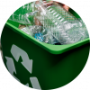 A green plastic trash can filled with recyclable items